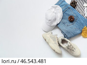 Стильные женские туфли, кепка, джинсы, свитер, наручные часы и осенний декор на белом фоне. Стоковое фото, фотограф Pixel_shot / Фотобанк Лори