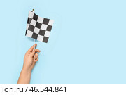 Женская рука с гоночным флагом на цветном фоне. Стоковое фото, фотограф Pixel_shot / Фотобанк Лори