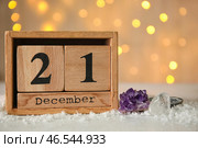 Календарь с датой 21 ДЕКАБРЯ и драгоценными камнями на снегу на фоне размытых огней. Зимнее солнцестояние. Стоковое фото, фотограф Pixel_shot / Фотобанк Лори