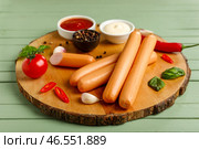 Доска вкусных колбасок с базиликом и чили на зеленом деревянном фоне. Стоковое фото, фотограф Pixel_shot / Фотобанк Лори