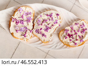 Тарелка сандвичей со вкусным сливочным сыром и сиреневыми цветами на светлом плиточном столе, крупный план. Стоковое фото, фотограф Pixel_shot / Фотобанк Лори