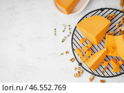 Охладительная решетка с кусочками вкусного чеддер-сыра на светлом фоне. Стоковое фото, фотограф Pixel_shot / Фотобанк Лори