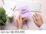 Женщина с напоминанием "не забыть" использует компьютер на розовом фоне плитки. Стоковое фото, фотограф Pixel_shot / Фотобанк Лори