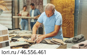 Elderly male shopper looks closely at carpet samples in a hardware store. Стоковое видео, видеограф Яков Филимонов / Фотобанк Лори