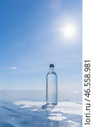 Glass bottle with cold natural drinking water stands on ice of frozen Baikal Lake on cold sunny winter day. Advertising and branding of drinking fresh ecological water. Nature background. Copy space. Стоковое фото, фотограф Виктория Катьянова / Фотобанк Лори