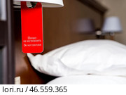 A hotel room with a red sign that says "Please do not disturb." The concept of a hotel stay. Стоковое фото, фотограф Photojuli / Фотобанк Лори