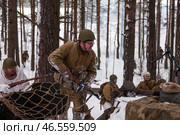 Sestroretsk, Russia - February 19, 2023: Snow-covered landscape sets the stage for a group of soldiers engaged in a reenactment of a historic winter battle. Редакционное фото, фотограф Aleksandr Golubev / Фотобанк Лори