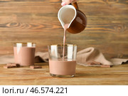 Наливание вкусного шоколадного молока из кувшина в стакан на деревянном фоне. Стоковое фото, фотограф Pixel_shot / Фотобанк Лори