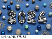 Фигура 2024 из фольгированных шаров с рождественскими украшениями на голубом фоне. Стоковое фото, фотограф Pixel_shot / Фотобанк Лори