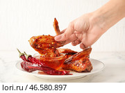 Женщина макает жареные куриные крылышки в миску с горячим медом на светлом фоне, крупным планом. Стоковое фото, фотограф Pixel_shot / Фотобанк Лори