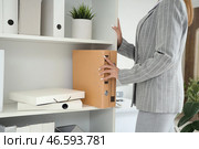 Молодая бизнесвумен берет папку с документами с полки в офисе, крупный план. Стоковое фото, фотограф Pixel_shot / Фотобанк Лори