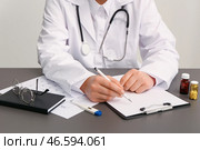 Женщина-врач записывает рецепт на медицинском столе. Близкий план. Стоковое фото, фотограф Pixel_shot / Фотобанк Лори