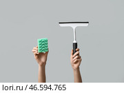 Женские руки с губкой и скребком на сером фоне. Стоковое фото, фотограф Pixel_shot / Фотобанк Лори