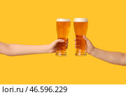 Женские руки с свежим пивом в пинтах на желтом фоне. Стоковое фото, фотограф Pixel_shot / Фотобанк Лори