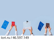Руки, держащие избирательную урну, паспорта и флаги ЕС на светлом фоне. Концепция выборов. Стоковое фото, фотограф Pixel_shot / Фотобанк Лори