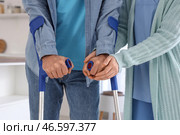 Медсестра помогает пожилому мужчине на костылях ходить на кухне, крупный план. Стоковое фото, фотограф Pixel_shot / Фотобанк Лори