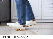 Мужчина поскальзывается на банановой кожуре на кухне, крупный план. Стоковое фото, фотограф Pixel_shot / Фотобанк Лори
