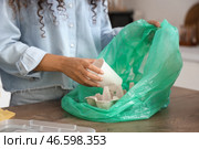 Молодая женщина бросает бумажный стаканчик в мусорный пакет на кухне, крупный план. Концепция сортировки отходов. Стоковое фото, фотограф Pixel_shot / Фотобанк Лори