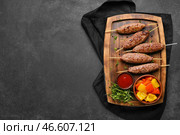 Деревянная доска для шашлыка с вкусным люля-кебабом, соусом и овощами-гриль на черном фоне. Стоковое фото, фотограф Pixel_shot / Фотобанк Лори