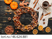 Красивый венок из желудей, чашка кофе, тыквы и фундук на черном деревянном фоне. Стоковое фото, фотограф Pixel_shot / Фотобанк Лори