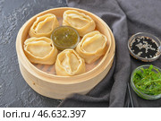 Пароварка с восточными пельменями и соусами на темном фоне. Стоковое фото, фотограф Pixel_shot / Фотобанк Лори