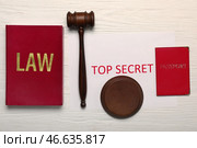 Молоток судьи, книга, паспорт и бумага с текстом СЕКРЕТНО на белом деревянном фоне. Стоковое фото, фотограф Pixel_shot / Фотобанк Лори
