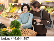 Married couple selects fresh parsley from supermarket counter. Стоковое фото, фотограф Яков Филимонов / Фотобанк Лори