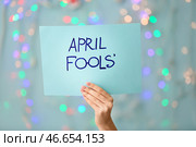 Женская рука держит лист бумаги с текстом APRIL FOOLS 'на цветном фоне. Стоковое фото, фотограф Pixel_shot / Фотобанк Лори