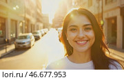 Smiling young woman in rays of setting sun on quiet street. Portrait of pretty girl in white tank top. Female university student walks around city. Стоковое AI-видео, аниматор Ирина / Фотобанк Лори
