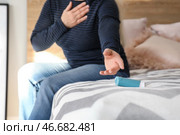 Зрелая женщина с приступом астмы принимает ингалятор из постели. Стоковое фото, фотограф Pixel_shot / Фотобанк Лори