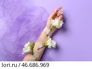 Женщина с проклеенными белыми цветами и вуалью на сиреневом фоне. Концепция ухода за руками. Стоковое фото, фотограф Pixel_shot / Фотобанк Лори