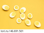 Половинки вкусных отваренных яиц с кусочками на желтом фоне. Стоковое фото, фотограф Pixel_shot / Фотобанк Лори