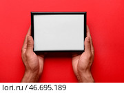 Мужчина держит пустую фоторамку на красном фоне. Стоковое фото, фотограф Pixel_shot / Фотобанк Лори