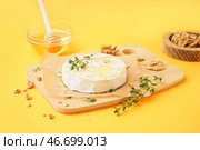 Деревянная доска с вкусным запеченным сыром Камамбер на желтом фоне. Стоковое фото, фотограф Pixel_shot / Фотобанк Лори