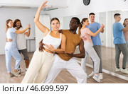 Joyful young adult couples learning passionate pair dancing during practicing in choreography class. Стоковое фото, фотограф Яков Филимонов / Фотобанк Лори