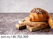 Деревянная доска с лакомым круассаном с шоколадом и орехами на темном столе. Стоковое фото, фотограф Pixel_shot / Фотобанк Лори