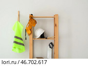 Стеллаж со строительными принадлежностями и светоотражающим жилетом на светлой стене. Стоковое фото, фотограф Pixel_shot / Фотобанк Лори