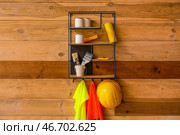 Полка со строительными принадлежностями и светоотражающими жилетами на деревянной стене. Стоковое фото, фотограф Pixel_shot / Фотобанк Лори