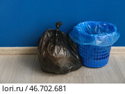 Полный мусорный мешок и пустой мусорный бак возле синей стены. Стоковое фото, фотограф Pixel_shot / Фотобанк Лори