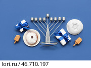 Композиция для празднования Хануки с менорой, пончиком, подарочными коробками и дрейделами на синем фоне. Стоковое фото, фотограф Pixel_shot / Фотобанк Лори
