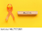 МАРТ и оранжевая лента на жёлтом фоне. Месяц осведомлённости о рассеянном склерозе. Стоковое фото, фотограф Pixel_shot / Фотобанк Лори