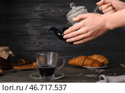 Женщина наливает синий чай из чайника в чашку на черном деревянном фоне. Стоковое фото, фотограф Pixel_shot / Фотобанк Лори