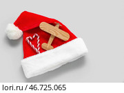 Шапка Санты, конфеты и деревянный самолет на белом фоне. Концепция рождественских каникул. Стоковое фото, фотограф Pixel_shot / Фотобанк Лори
