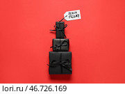 Подарочные коробки и бумажный ярлык на красном фоне. Распродажа в Черную пятницу. Стоковое фото, фотограф Pixel_shot / Фотобанк Лори