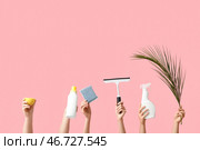 Женские руки держат губку, пальмовый лист, бутылки с моющим средством, лимон и скребок на розовом фоне. Стоковое фото, фотограф Pixel_shot / Фотобанк Лори