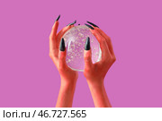 Руки дьявола с хрустальным шаром на розовом фоне. Празднование Хэллоуина. Стоковое фото, фотограф Pixel_shot / Фотобанк Лори
