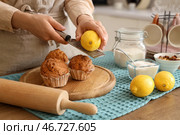 Женщина натирает цедру лимона на маффины за столом на кухне, крупный план. Стоковое фото, фотограф Pixel_shot / Фотобанк Лори