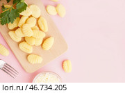 Деревянная доска с вкусными ньокки, тертым сыром и петрушкой на розовом фоне. Стоковое фото, фотограф Pixel_shot / Фотобанк Лори