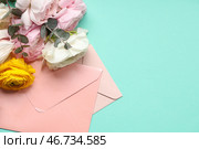 Красивые цветы ранункулюса с эвкалиптом и конвертами на бирюзовом фоне. Стоковое фото, фотограф Pixel_shot / Фотобанк Лори
