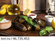 Разделочная доска с вкусными долмами (фаршированные виноградные листья), сметаной и специями на деревянном столе. Стоковое фото, фотограф Pixel_shot / Фотобанк Лори